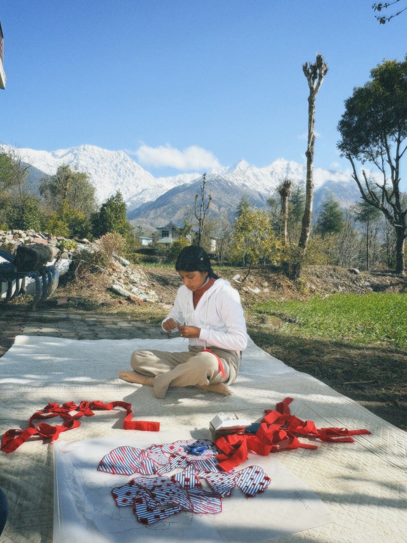 Woman sewing under the Dhauladhar peaks