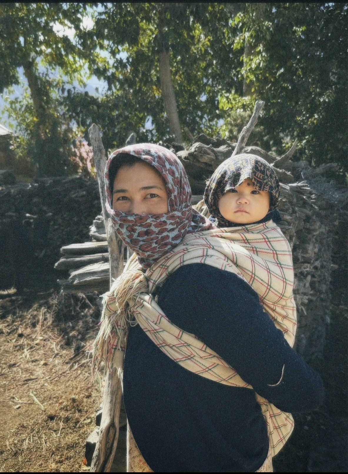 Mother carrying her child on her back in a Himalayan village